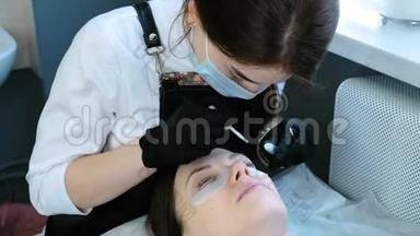 <strong>美容治疗</strong>。 <strong>美容师</strong>把卷发器贴在女人的眼皮上。